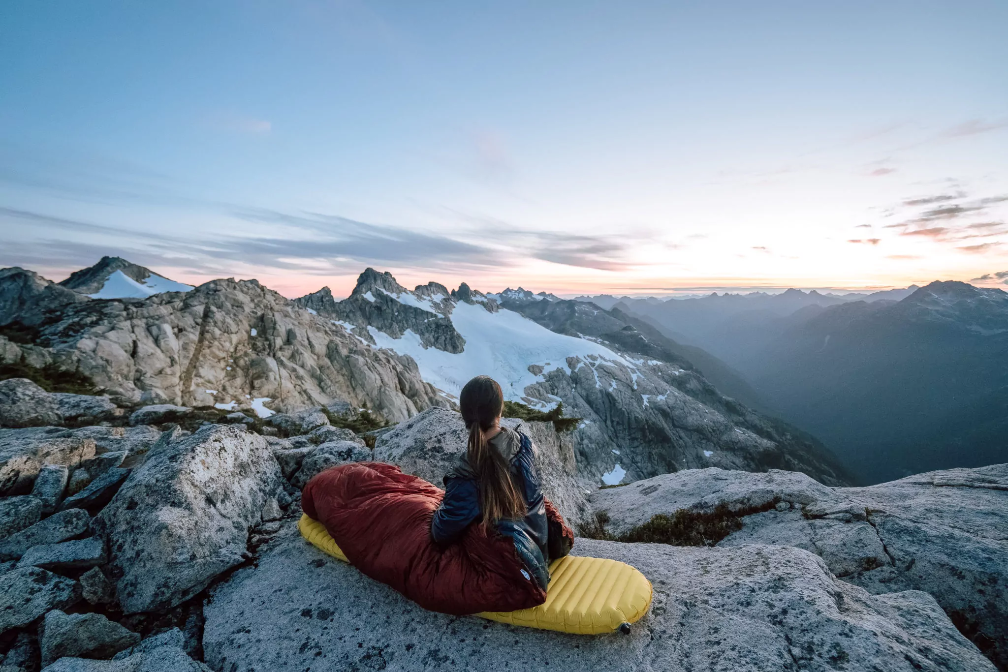 a person sitting in a red diamondback top quilt on a mountain overlook