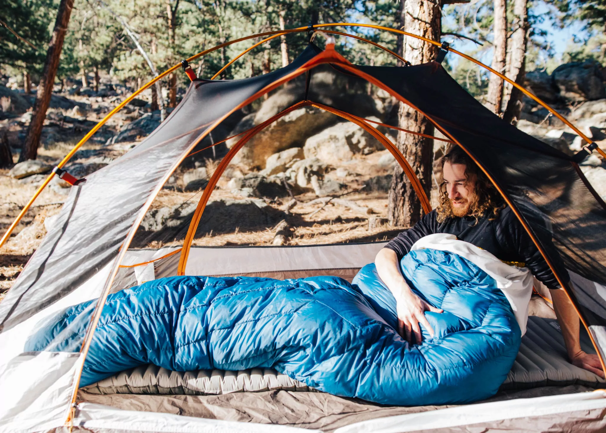 a person in a blue diamondback top quilt under a tent